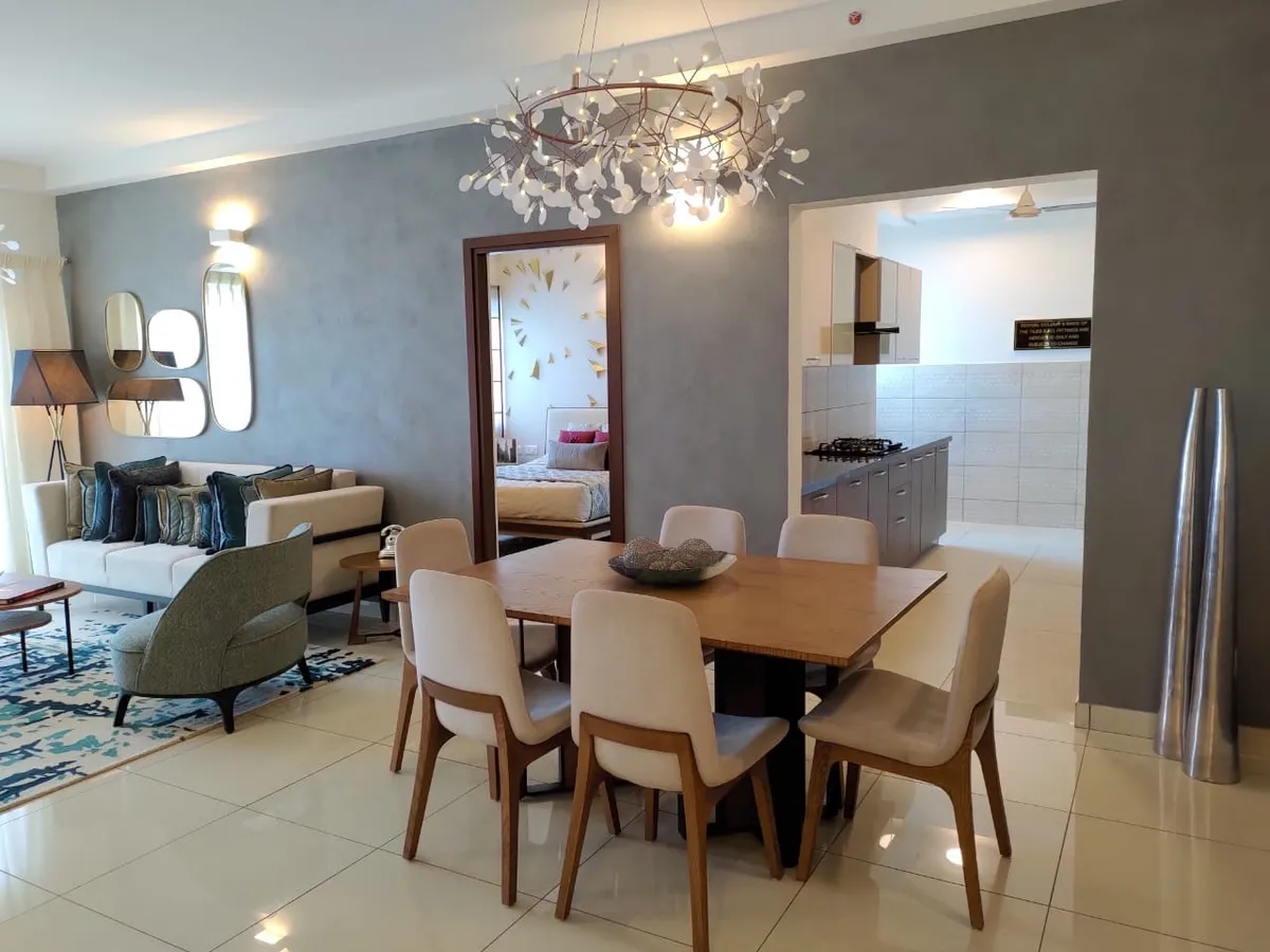 Open-plan living-dining space with a branch-style pendant chandelier over a wooden dining table, a mirror cluster on a textured grey wall