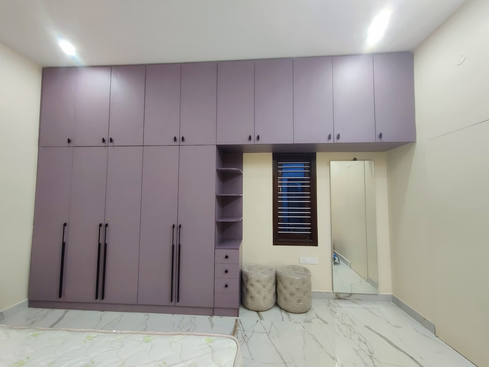Bedroom with a full-height mauve wardrobe wall including loft storage and an open shelf column, a full-length mirror