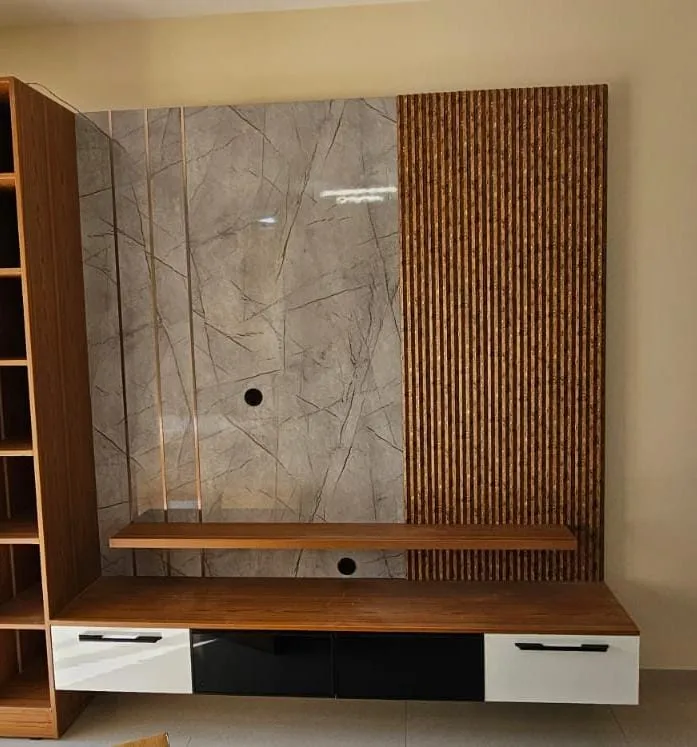 Living room TV wall in grey-veined marble with a vertical fluted-wood accent strip, over a floating wood-and-white TV console with black glass shutters.