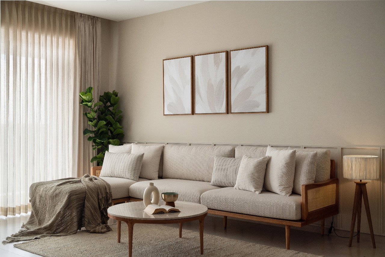 Render of a living room with a beige cane-and-wood sectional sofa, triptych framed wall art, a round wood coffee table, sheer curtains