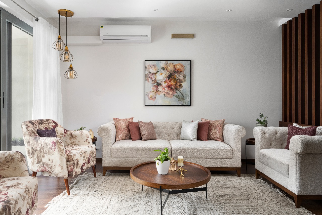 Living room with a tufted chesterfield-style beige sofa, floral-upholstered armchairs, a fluted dark-wood accent wall