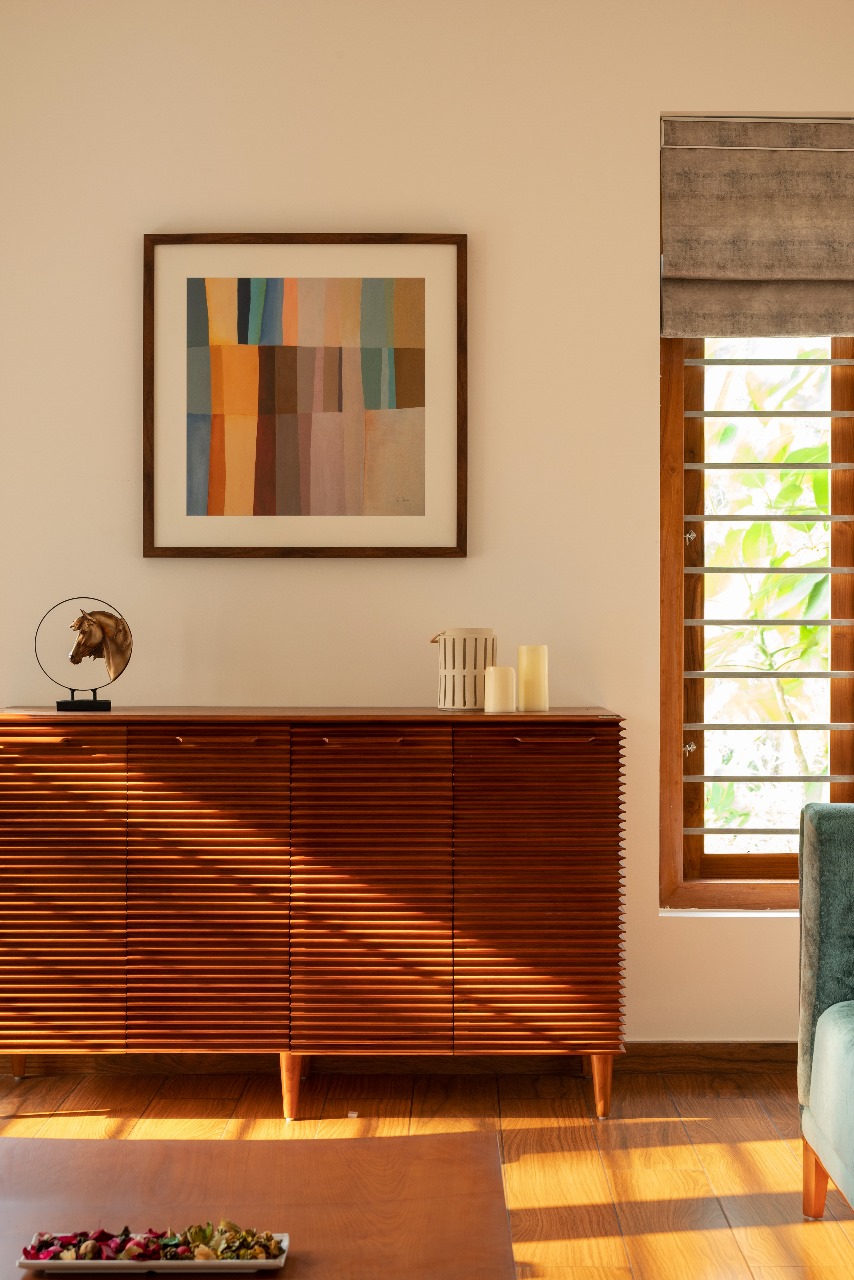 Living-room console vignette with a ribbed wood sideboard on tapered legs, a colour-block abstract framed print above, a bronze horse sculpture