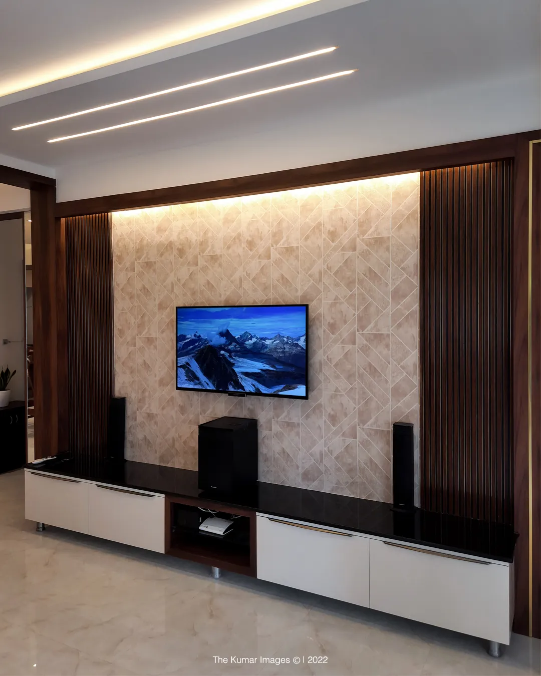 A TV wall with diagonal-pattern stone-look tile cladding flanked by fluted dark-wood panelling