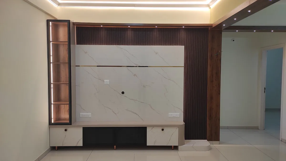 Unfurnished flat hall with a marble-look TV back panel split by a brass inlay line, walnut fluted panelling carrying up the return wall