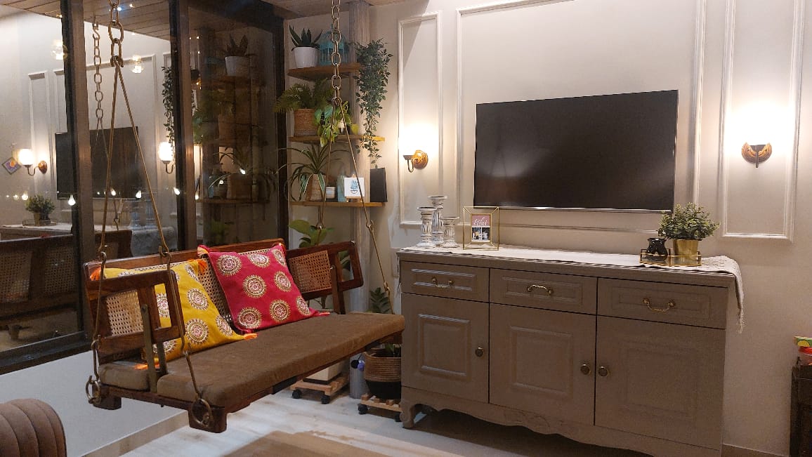 Living room with a cane-sided wooden hanging swing styled with yellow and red medallion-print cushions