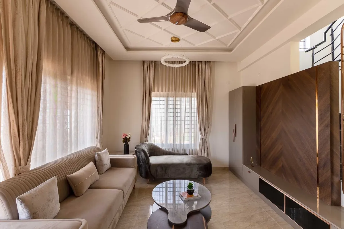 Living room with a beige channel-tufted sofa facing a grey velvet chaise, twin kidney-shaped coffee tables on marble-look tile