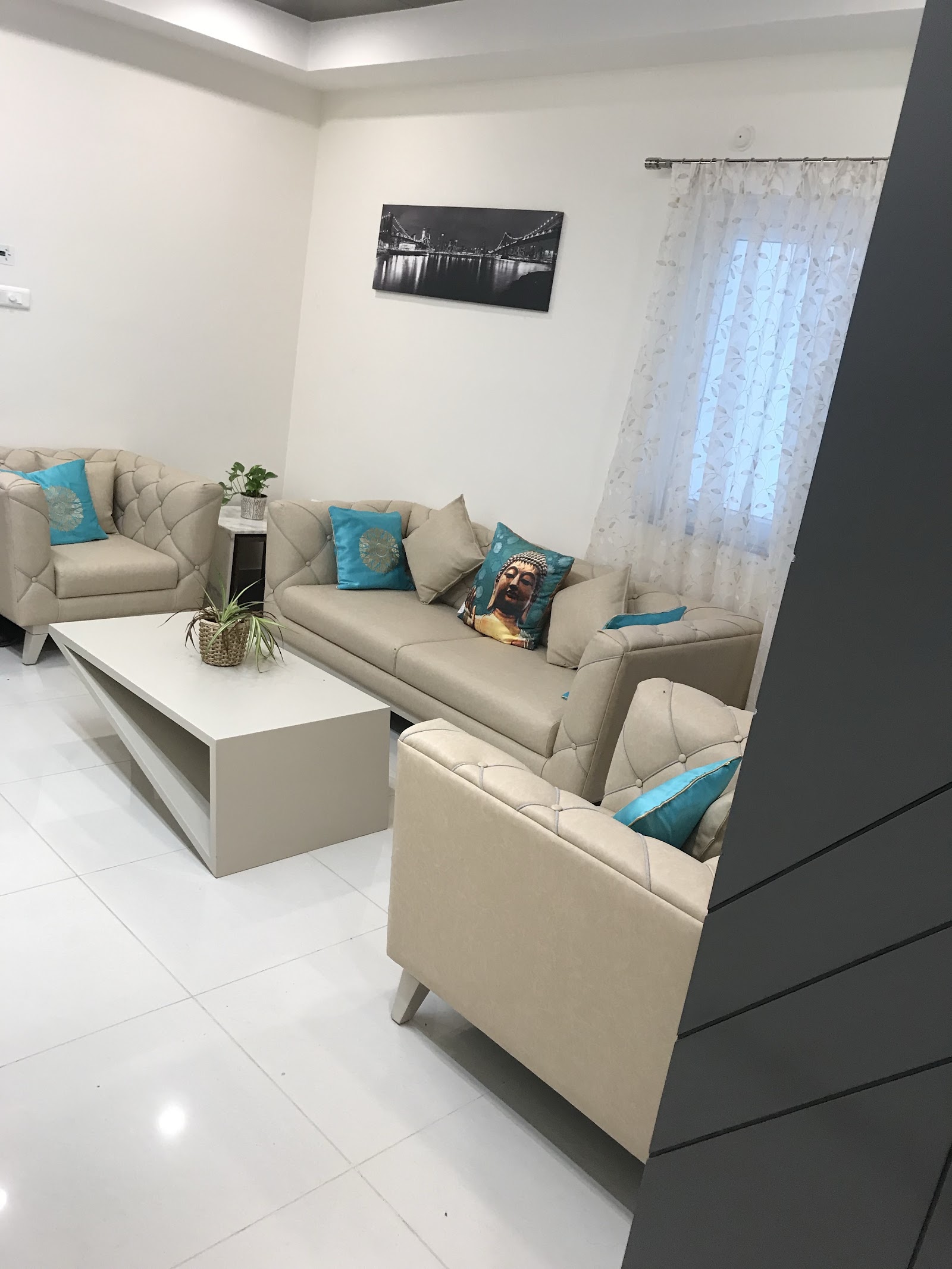 Living room with a beige tufted leather sofa set styled with teal accent cushions, a white geometric coffee table