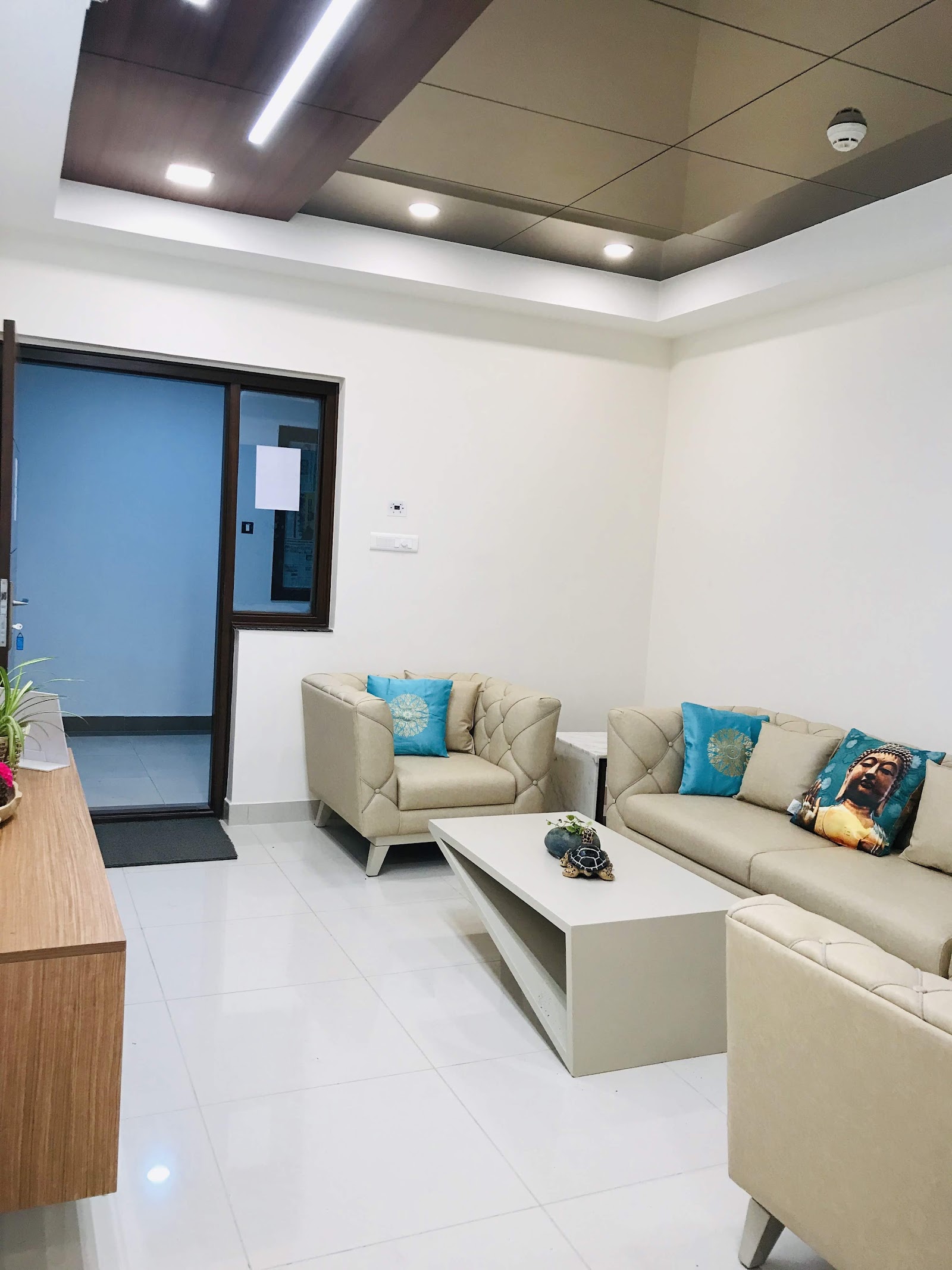 Real living room with a cream tufted leather sofa set, teal accent cushions including a Buddha print