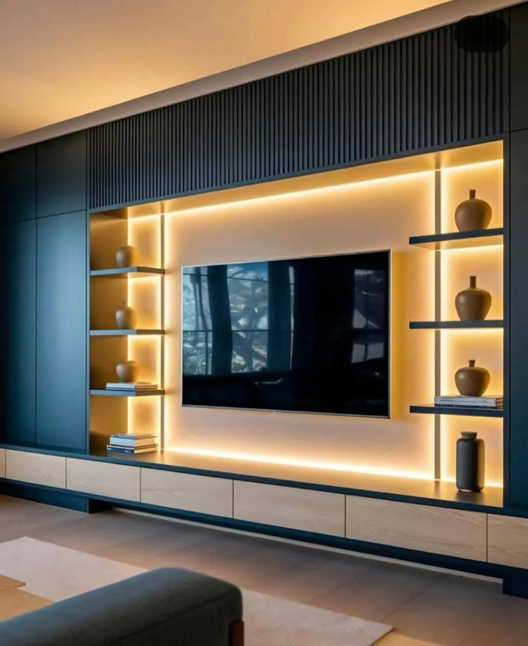 Render of a full-wall teal media unit with fluted panelling above, three warm-backlit open shelves holding stoneware vases on either side of the TV