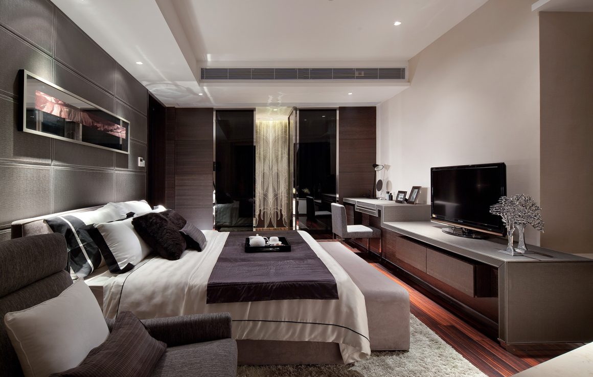 Luxury master bedroom with quilted grey leather-look wall panelling, a bench at the foot of the bed, a dark wood-floor TV console area