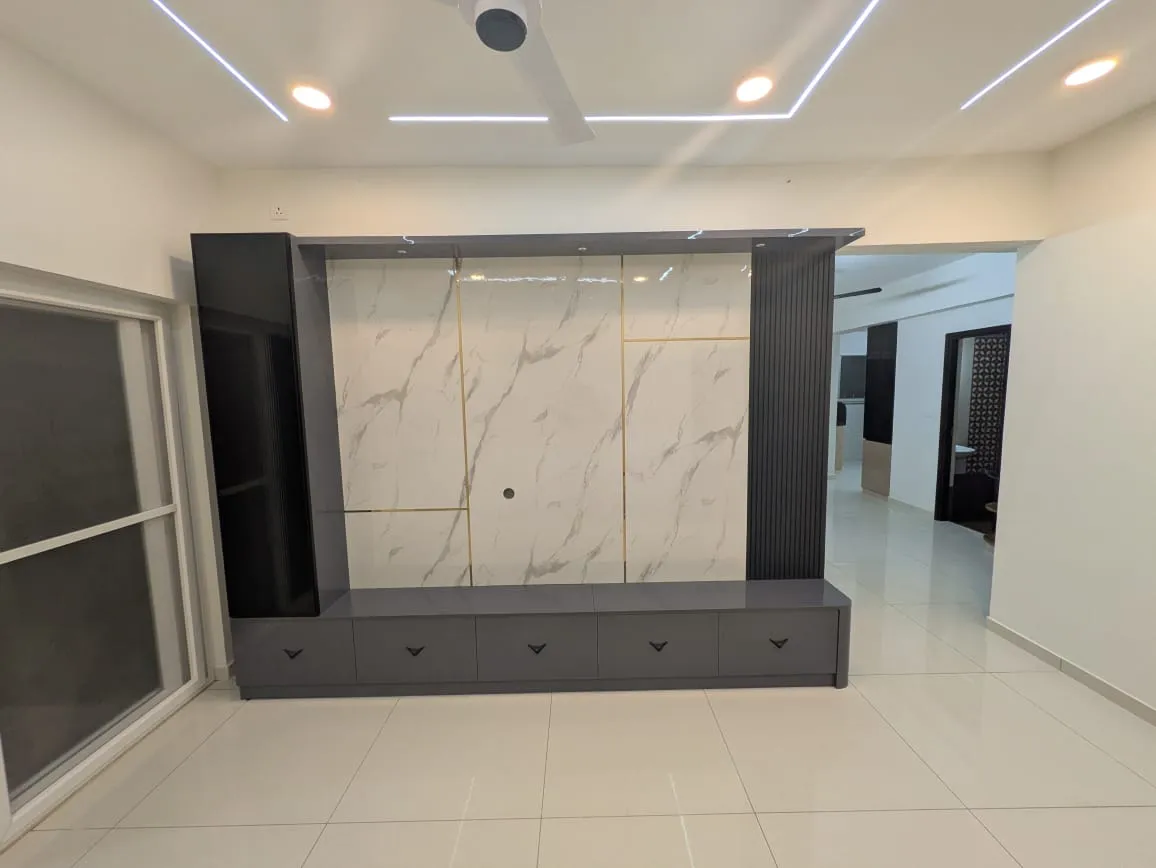 An empty living room TV wall with a gold-inlaid marble slab panel flanked by fluted grey pillars, a floating grey TV console