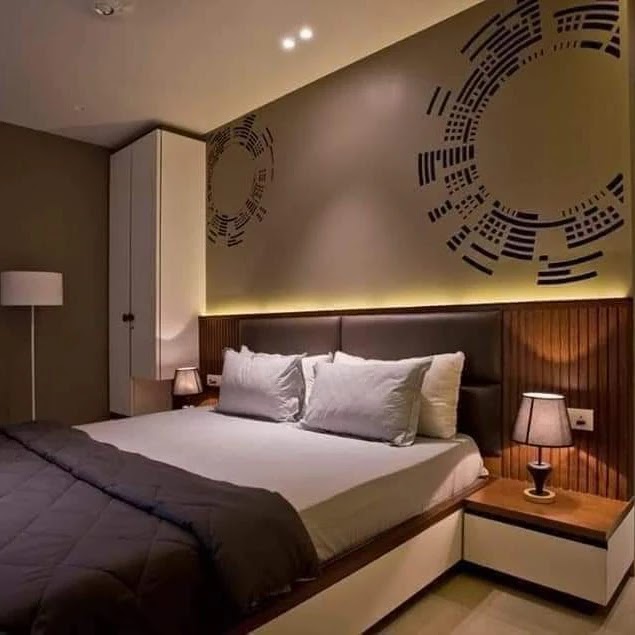 Bedroom with a dark accent wall featuring a large circular geometric wall-art motif, a wood-slat panelled headboard wall with cove lighting
