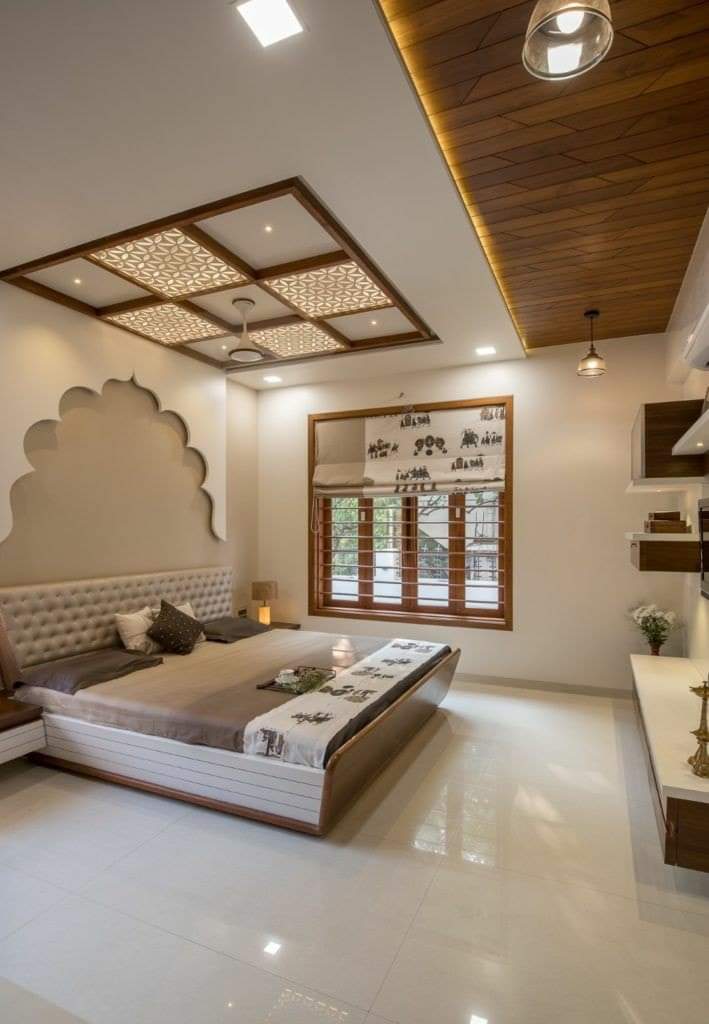 Master bedroom with a mihrab-arched wall niche behind a tufted headboard, under a backlit jaali-pattern false ceiling framed by wood panelling.
