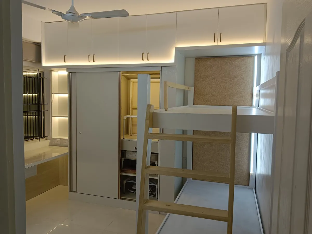 Kids' bedroom with a white loft bed and integrated sliding wardrobe beneath, accessed by a wood ladder.