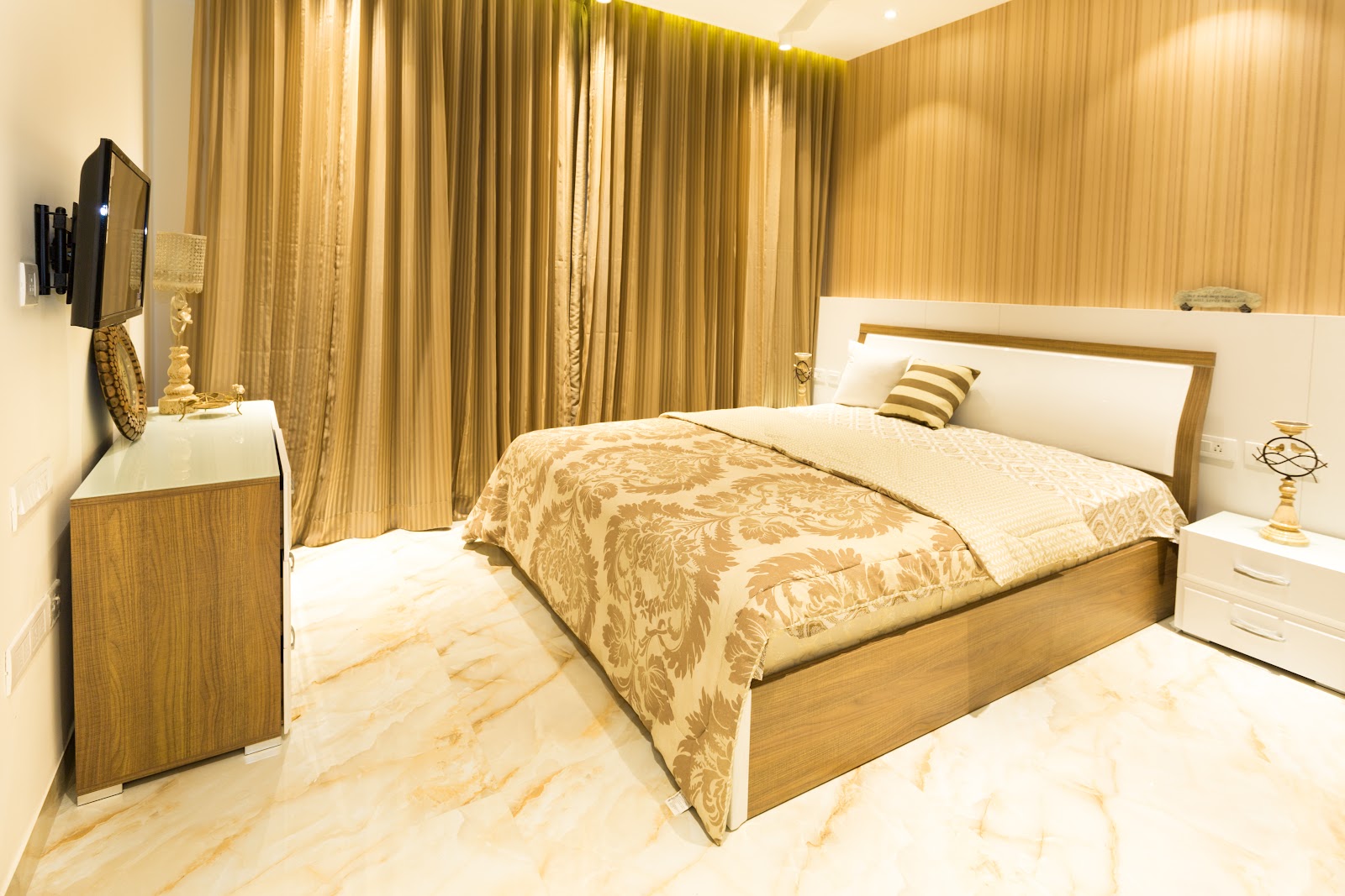 Bedroom with wood-veneer strip panelling behind the bed, marble flooring, and heavy gold damask curtains.
