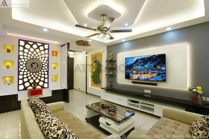 A render of a living room with a multi-layer cove-lit POP ceiling, a backlit Om mandala jaali wall panel beside illuminated display niches