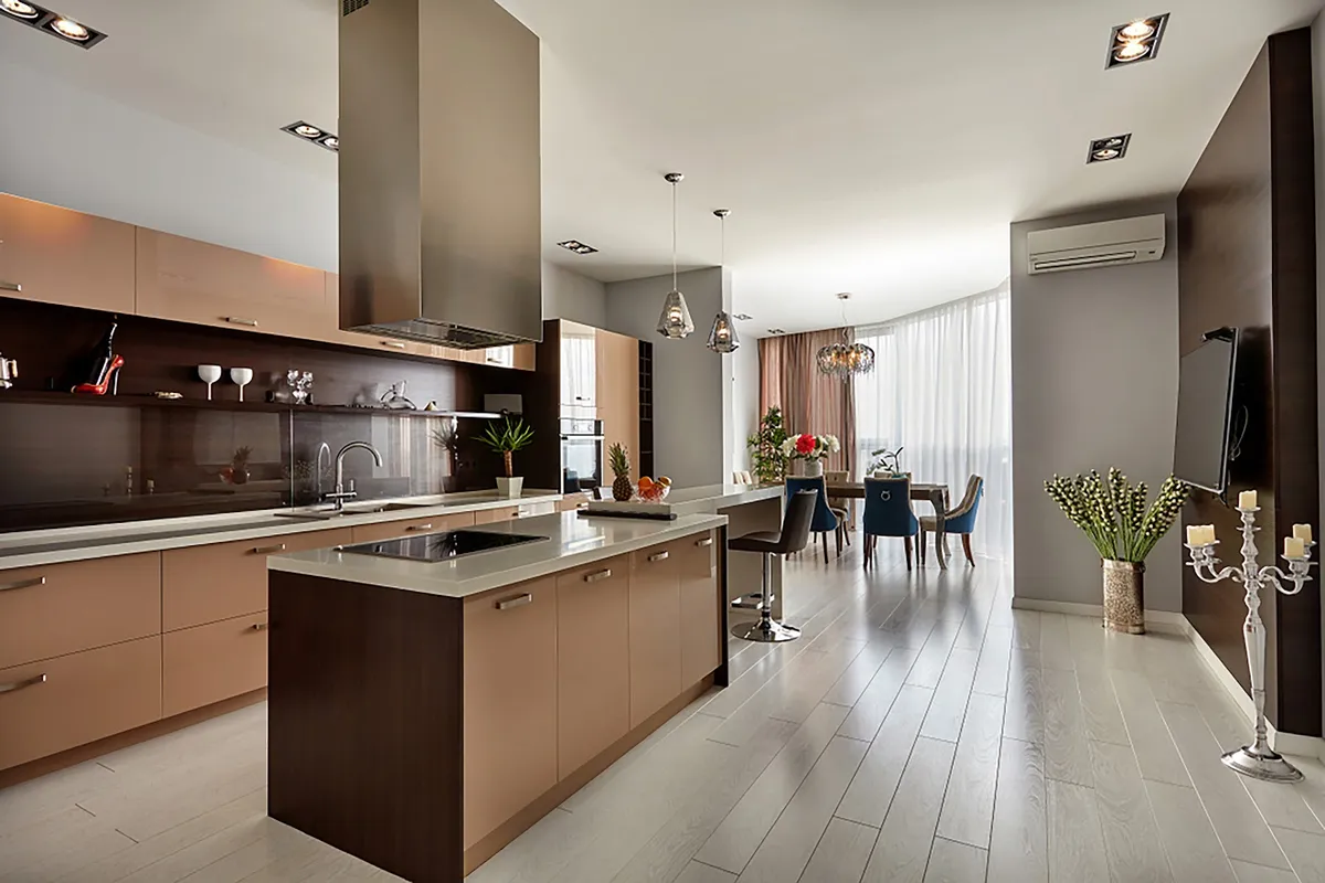 Open-plan kitchen, dining and living space with a two-tone wood kitchen island, glass pendant lights, a dining table with mixed upholstered chairs