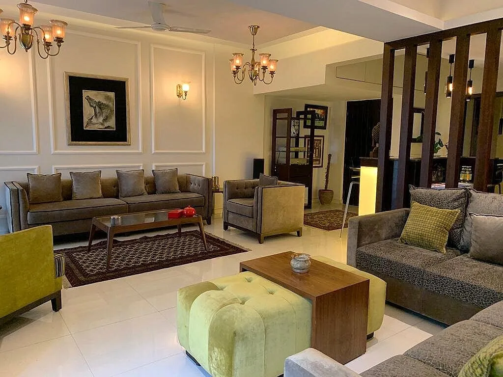 Long living room holding two seating groups - grey-brown velvet sofas with olive cushions