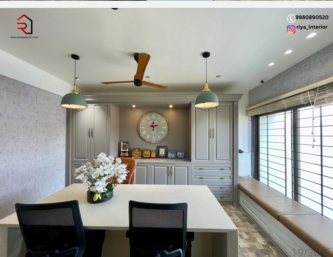 Home study/dining nook with grey raised-panel cabinetry framing a large wall clock and trophy display, twin pendant lights