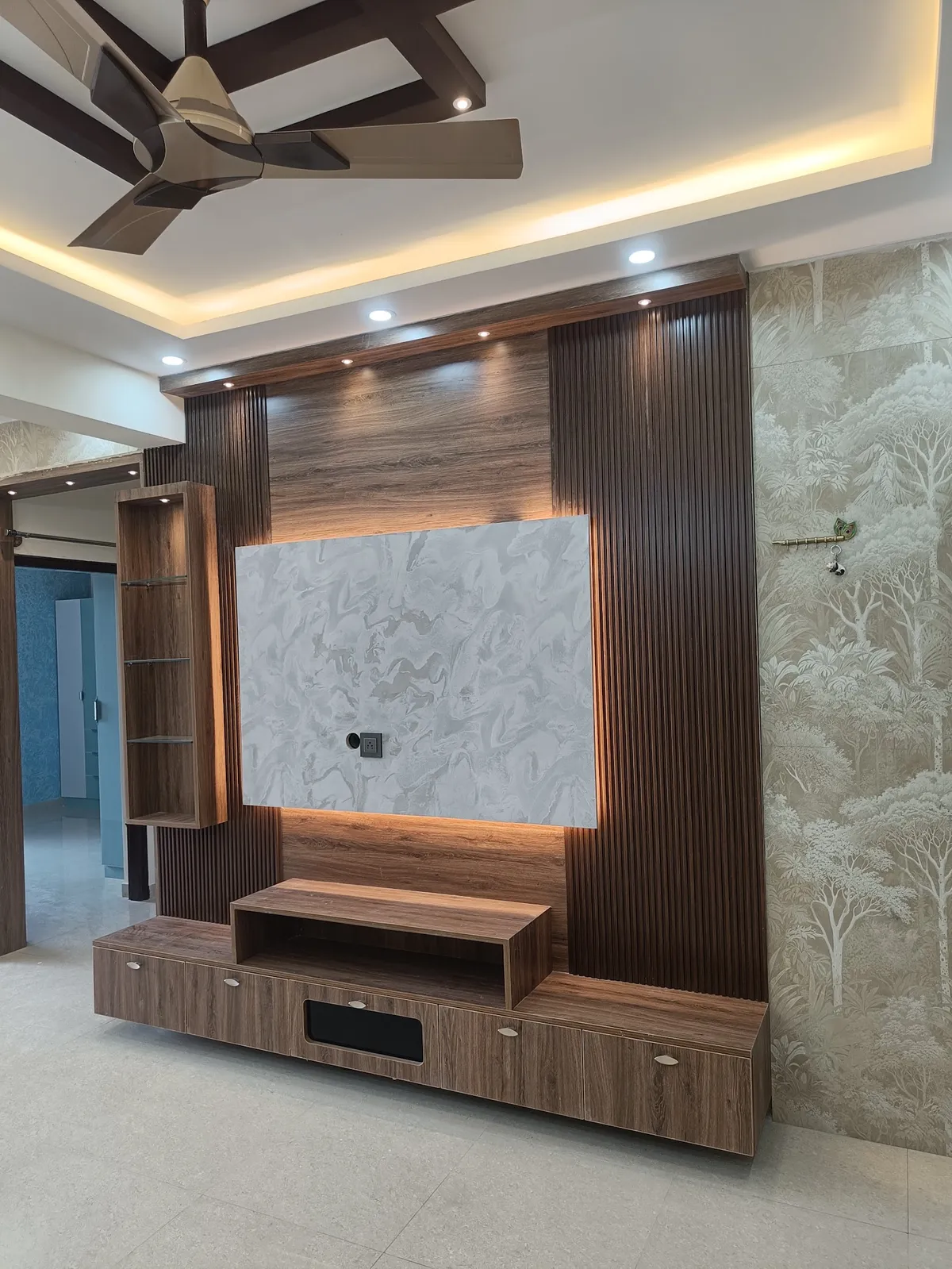 Empty living room whose walnut fluted TV wall frames a backlit grey marble-look panel