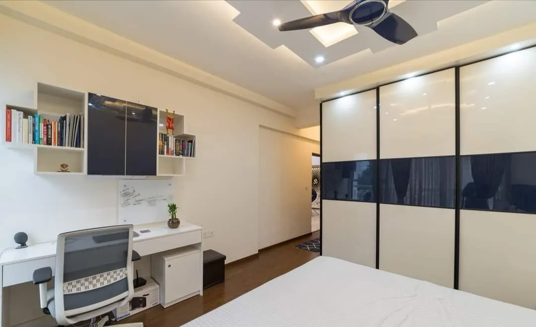 Master bedroom with a black-and-cream glossy sliding wardrobe, a built-in study desk with an open bookshelf