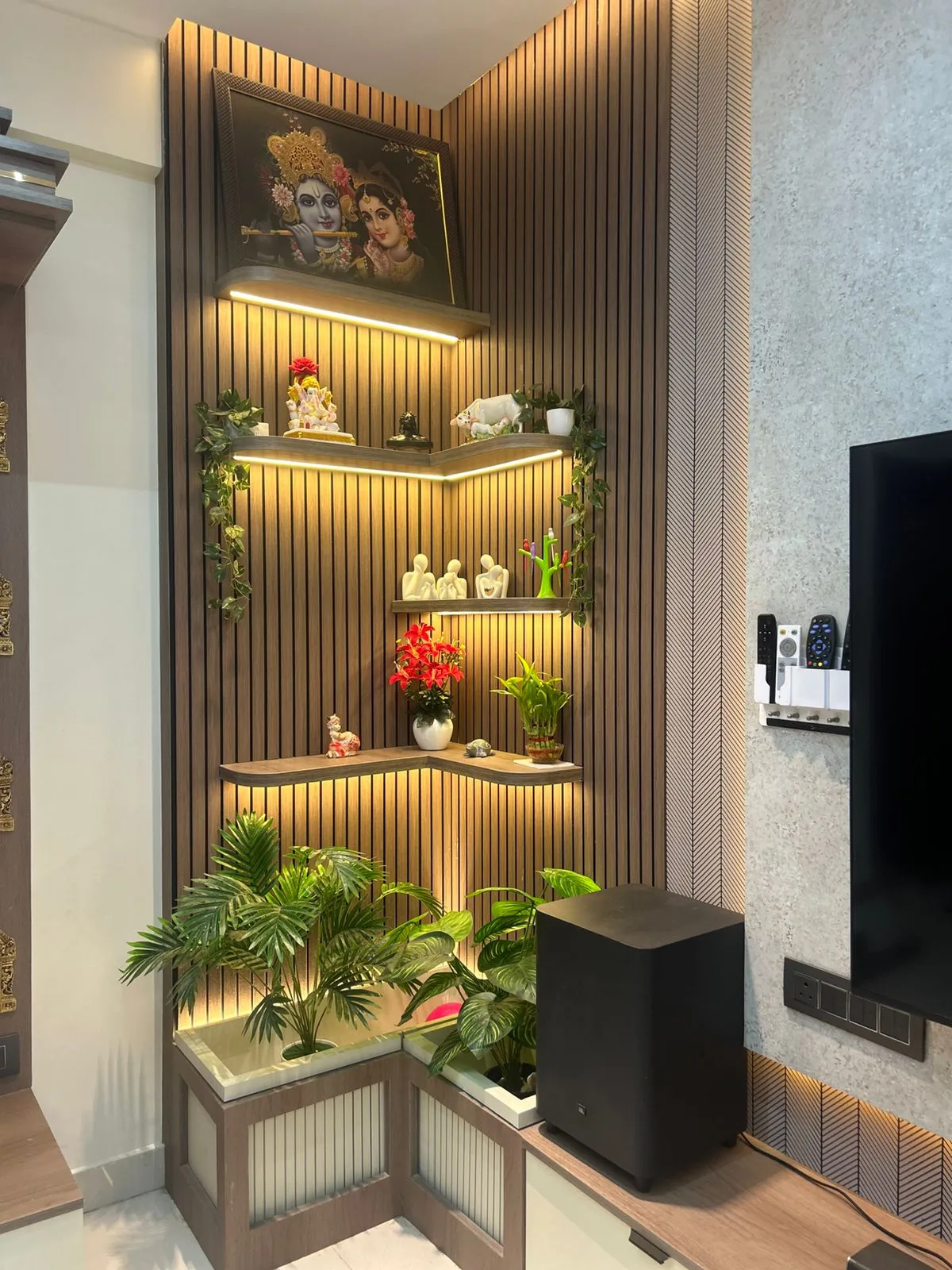 Corner display unit in vertical wooden slat fluting with three backlit L-shaped shelves of idols