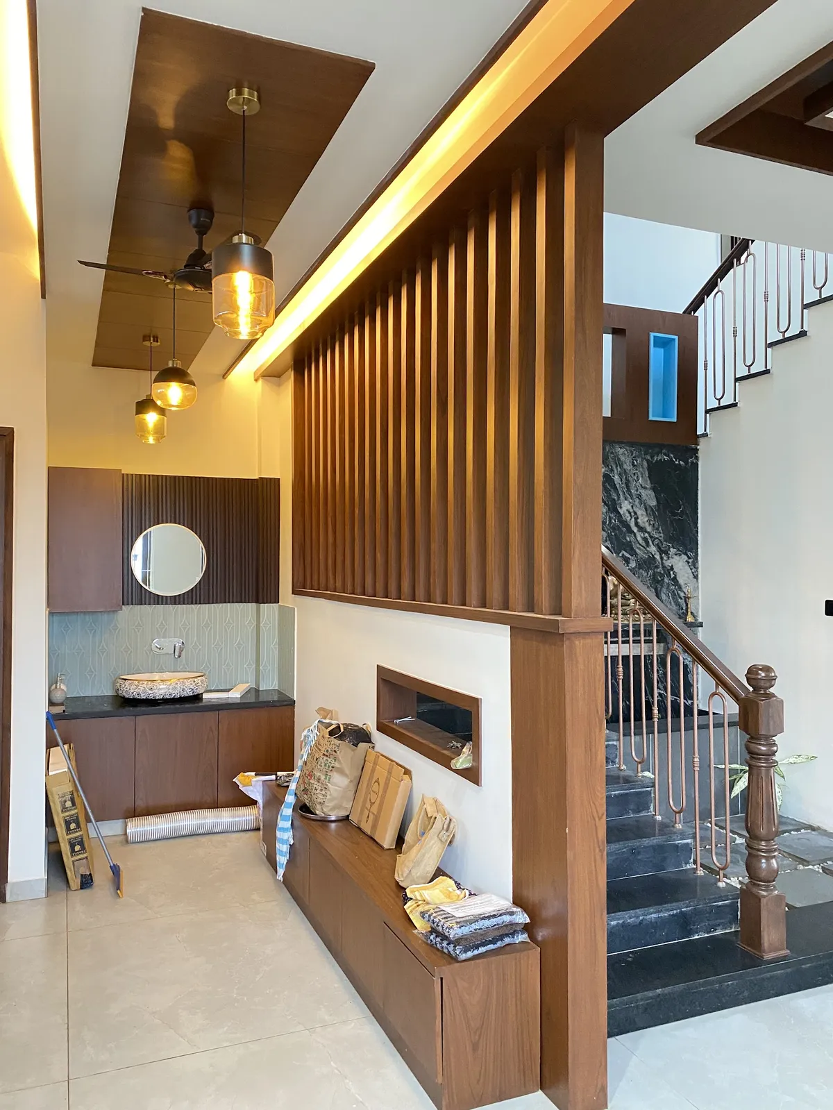 Entrance foyer with a backlit fluted-wood partition dividing the hallway from a marble-clad staircase, a built-in bench below it