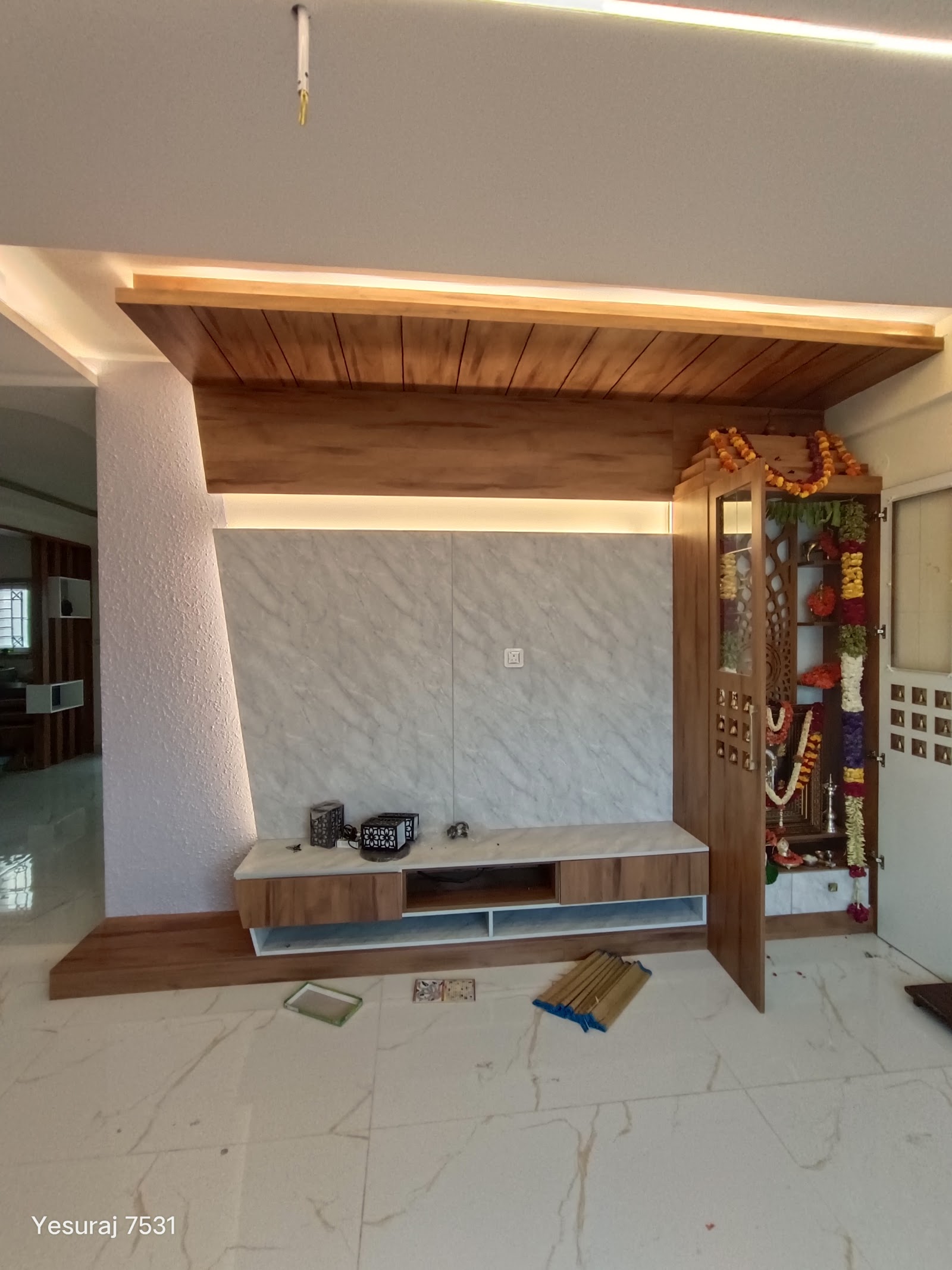 Living room TV wall in wood cove-lit panelling and marble-look cladding with a floating wood console