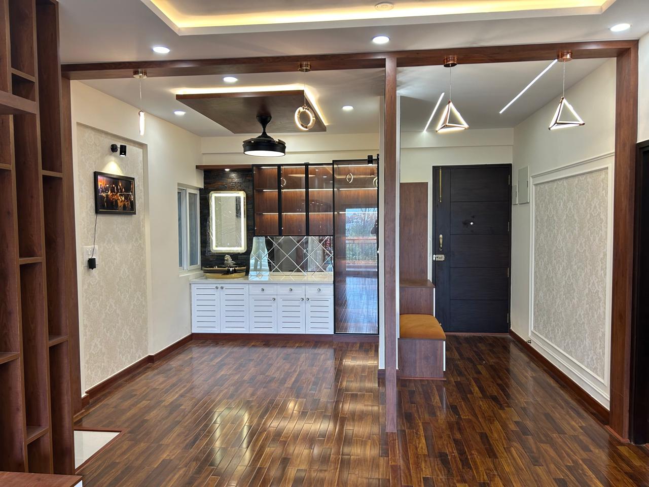 Entryway with walnut-tone herringbone-style wood flooring, a black panelled main door, a slatted-door shoe unit under a backlit mirror