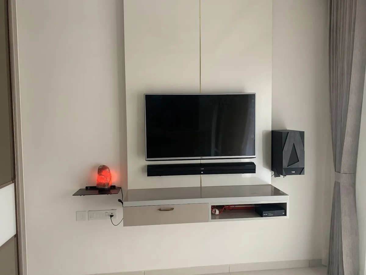 Living room TV wall with a floating console housing a soundbar and subwoofer, a thin gold inlay strip on the panel