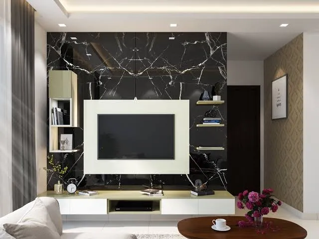 Render of a living room TV wall in black veined marble, framed by a cream open-shelf TV unit