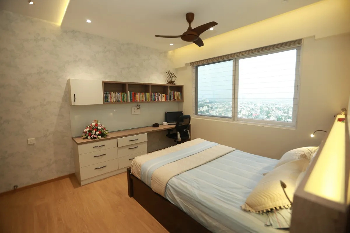 Bedroom with a built-in study run along the window wall - open bookshelf over a desk plus a six-drawer chest - beside a dark wood bed