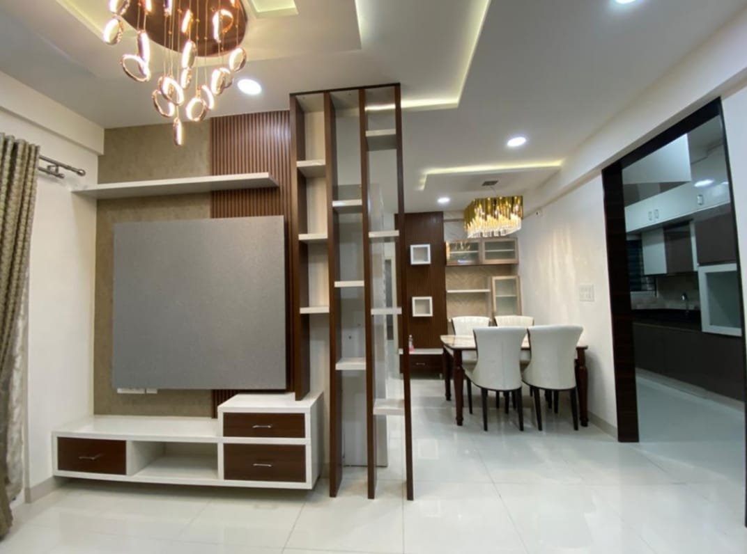 Open-plan living-dining space with a fluted-wood TV feature wall, a sculptural pendant chandelier, and a wood-and-glass crockery unit beside the dining table