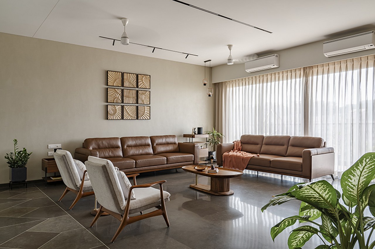 Living room with two tan leather sofas and cane-and-wood armchairs around an oval walnut coffee table
