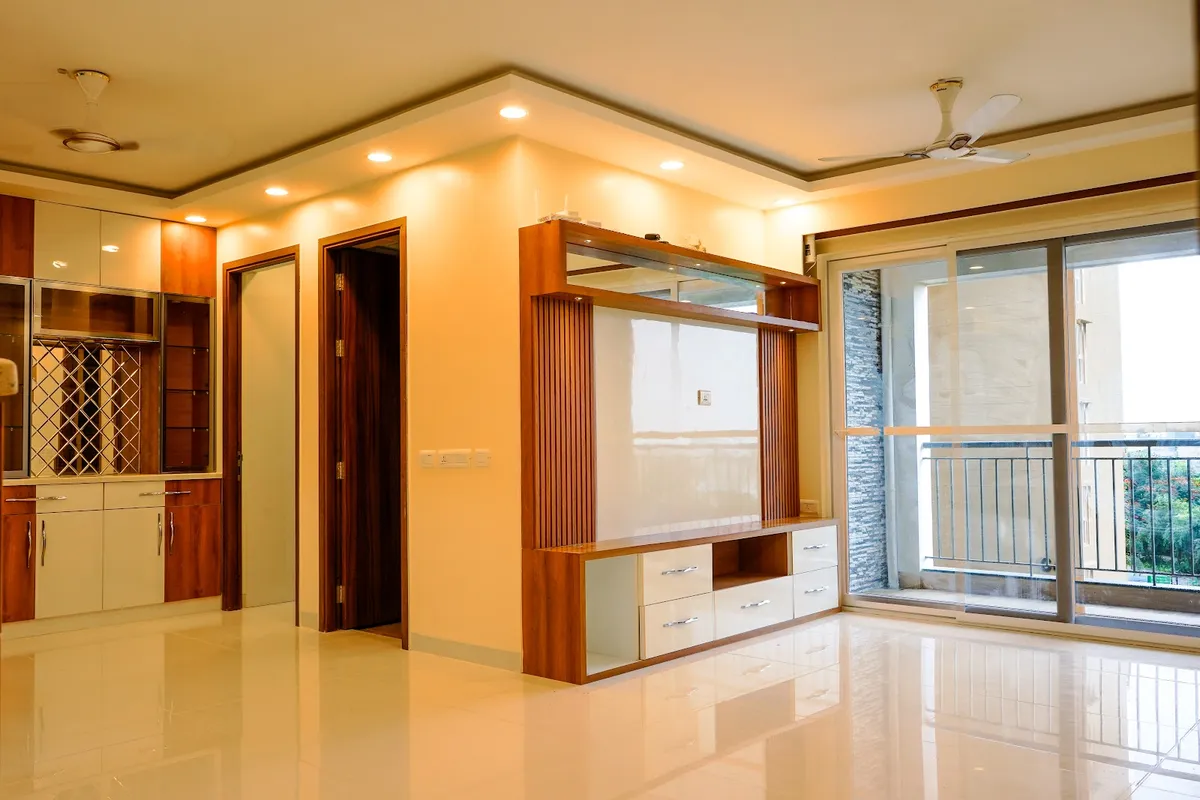 Empty apartment hall with a teak-framed TV unit with fluted side battens, white drawer fronts and a glass display shelf on the projecting wall
