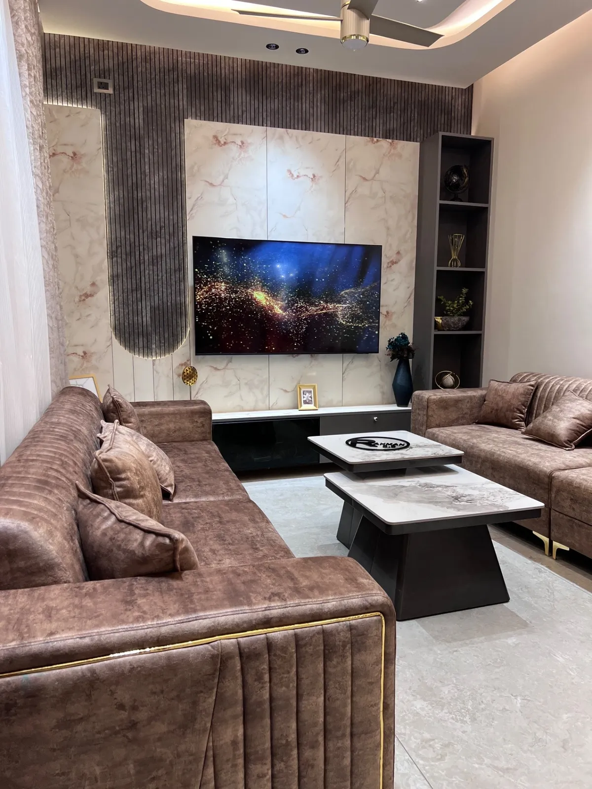 Living room where a brown fluted-wood wall wraps an arch motif around a pink-veined marble TV panel