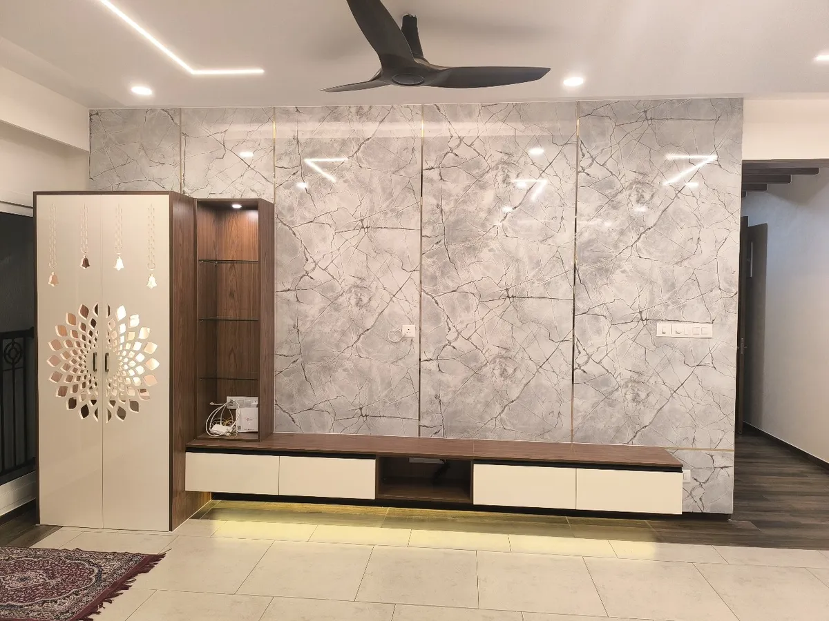 Living room wall clad in four bays of grey veined marble sheet split by thin gold strips