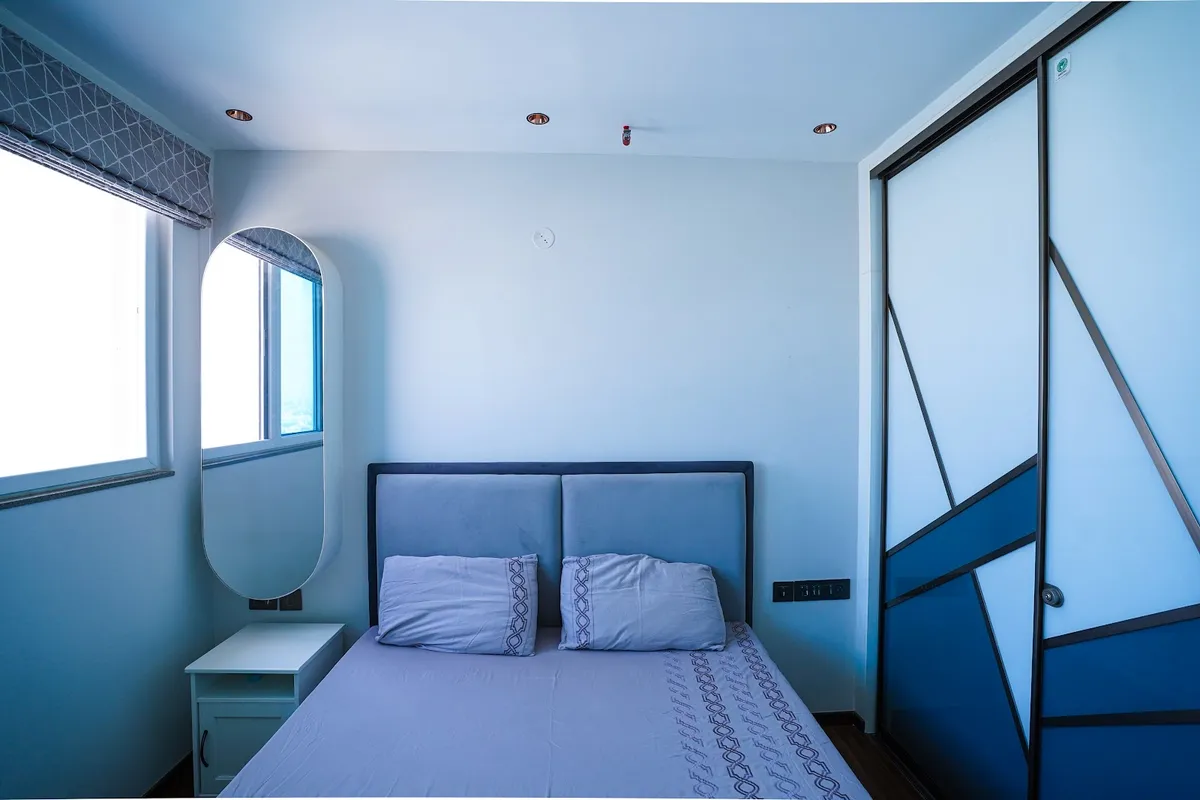 Small spare bedroom shot under a heavy blue cast - twin-panel upholstered headboard