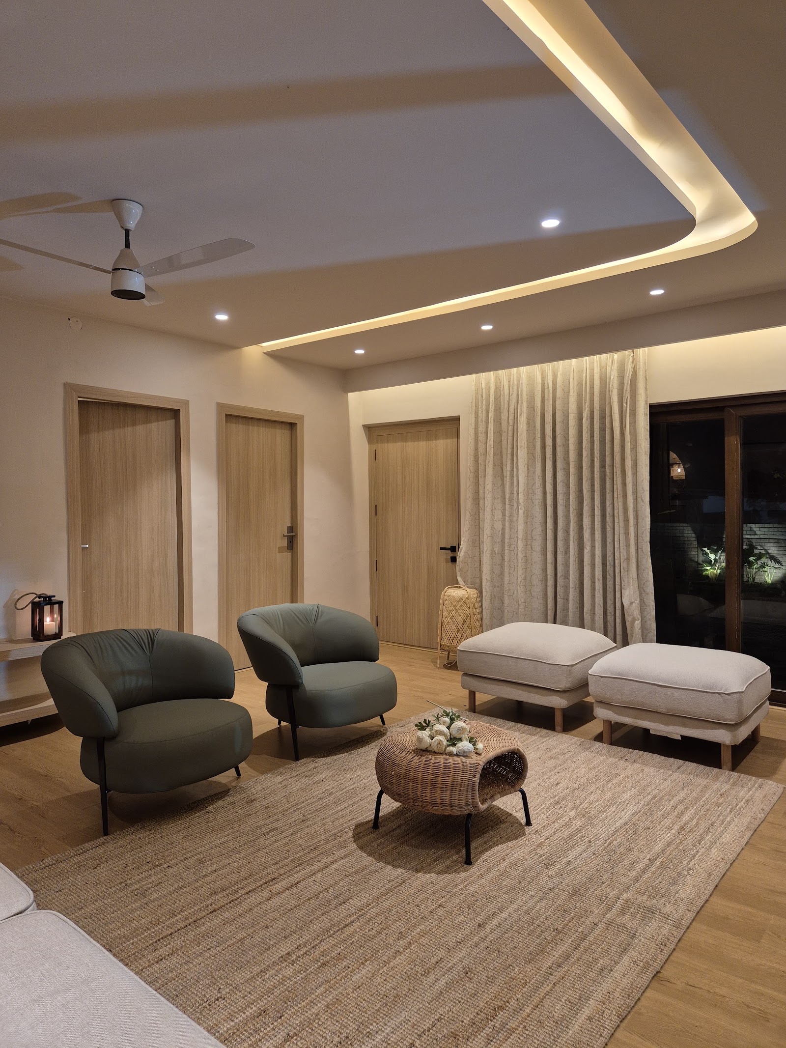 Living room with two olive-green curved armchairs and a wicker drum coffee table on a jute rug