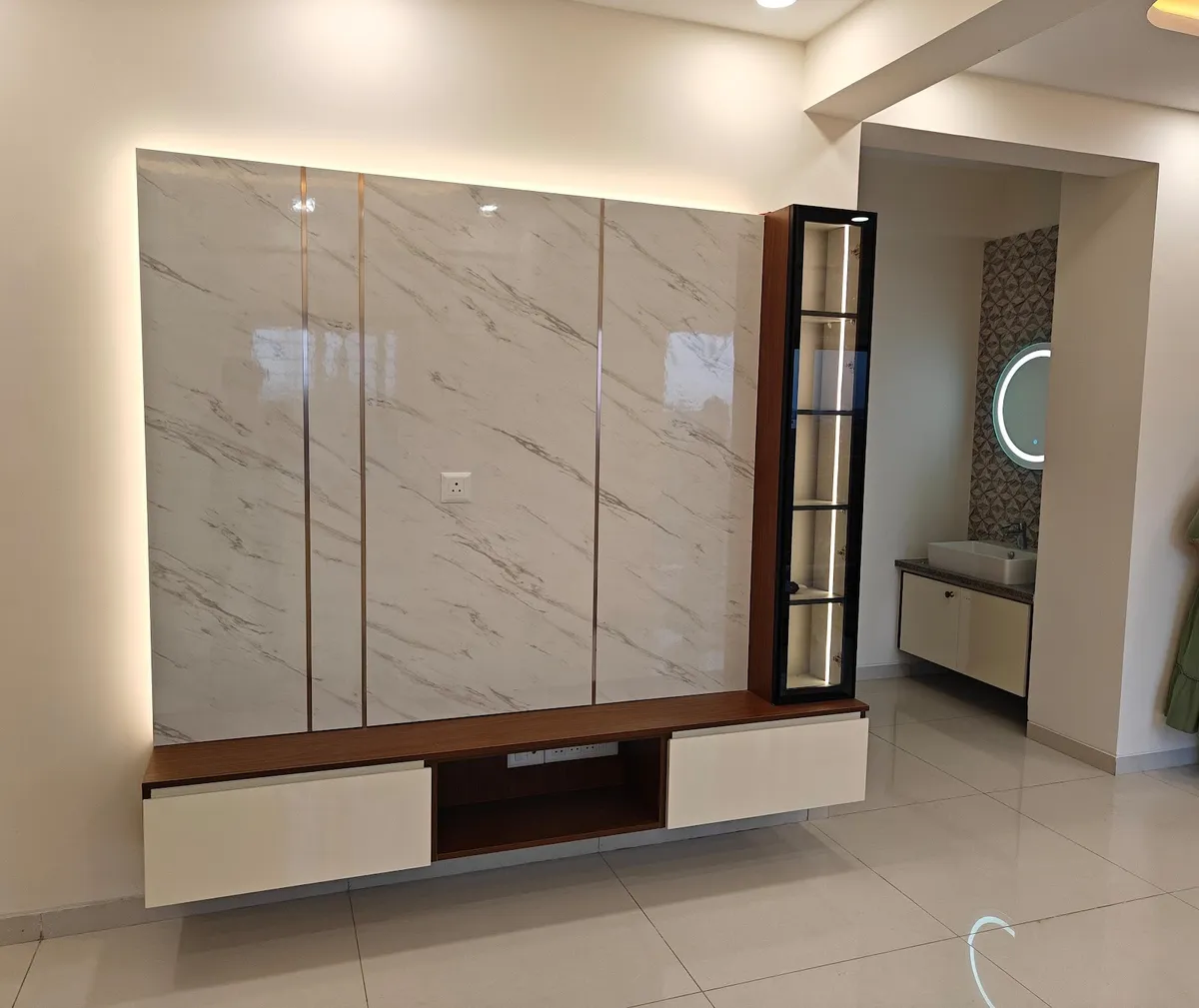 Handed-over TV wall of four high-gloss marble-look panels in a backlit halo, a walnut floating console with two ivory drawers and an open cable slot