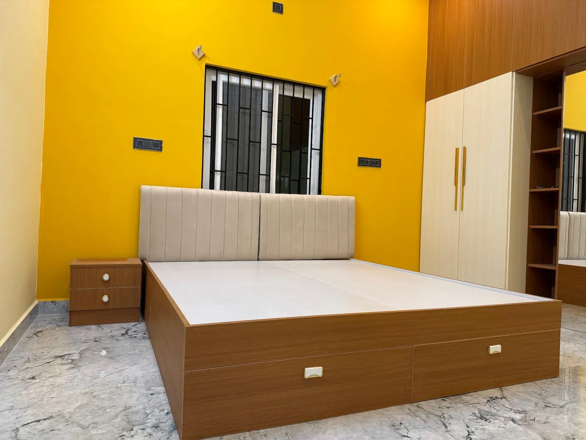 Bedroom with a bold yellow accent wall, a tufted cream upholstered headboard, a wood storage bed with drawer fronts, and a matching wardrobe with mirror.