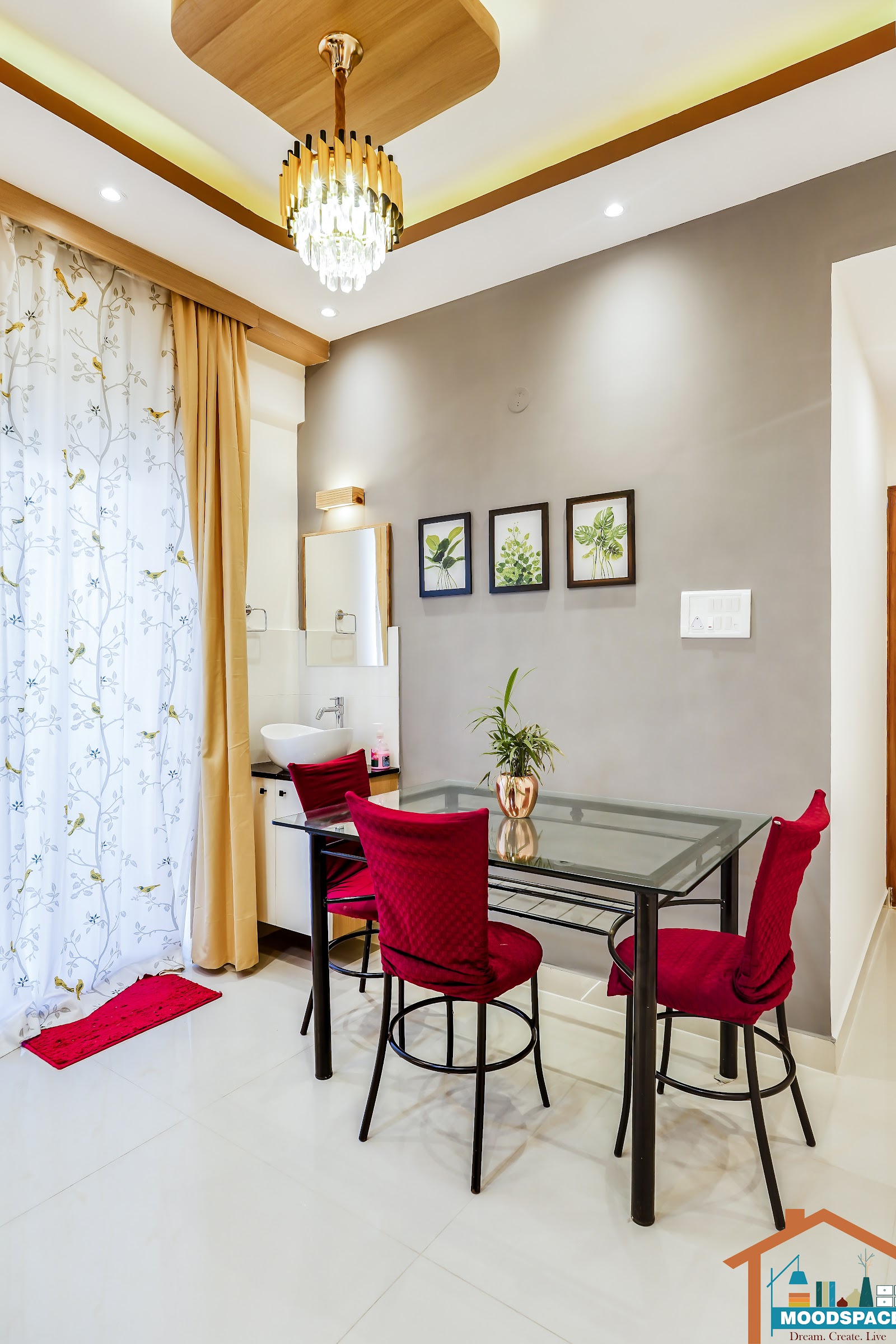 Real dining nook with red velvet-covered chairs around a glass-top table, a crystal chandelier under a wood ceiling cutout