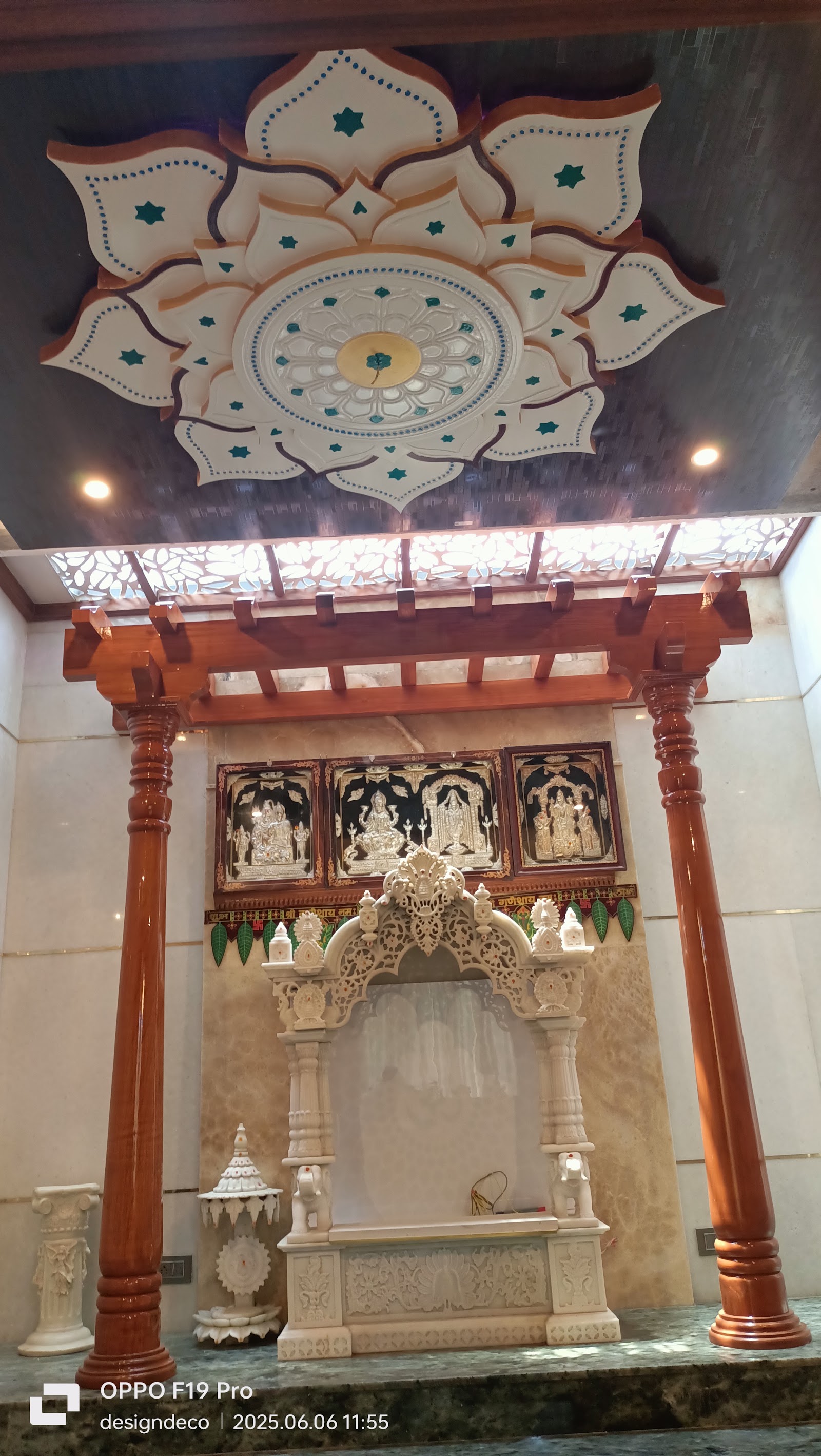 Dedicated pooja room with an ornate carved lotus ceiling medallion, a wood pergola-style entrance frame on turned pillars