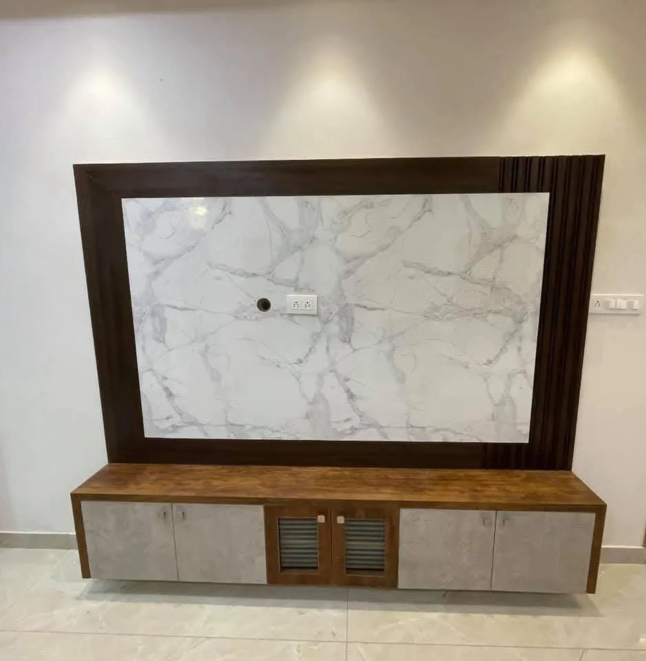 TV feature wall with a dark wood-framed white marble panel insert and fluted wood trim, above a floating TV console with cane-textured cabinet doors.