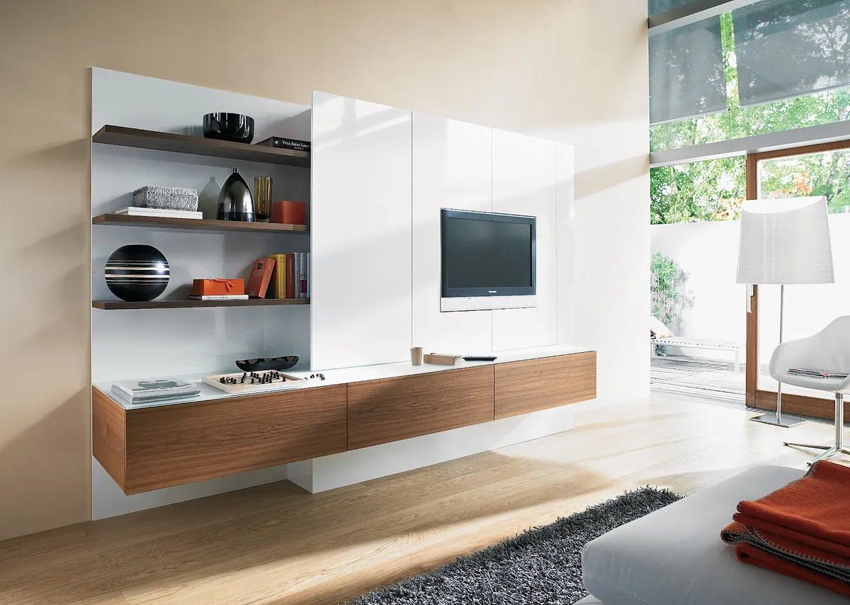 Living room with a fully wall-hung TV composition of white gloss panels, walnut floating drawers and three walnut shelves styled with a chess set and books
