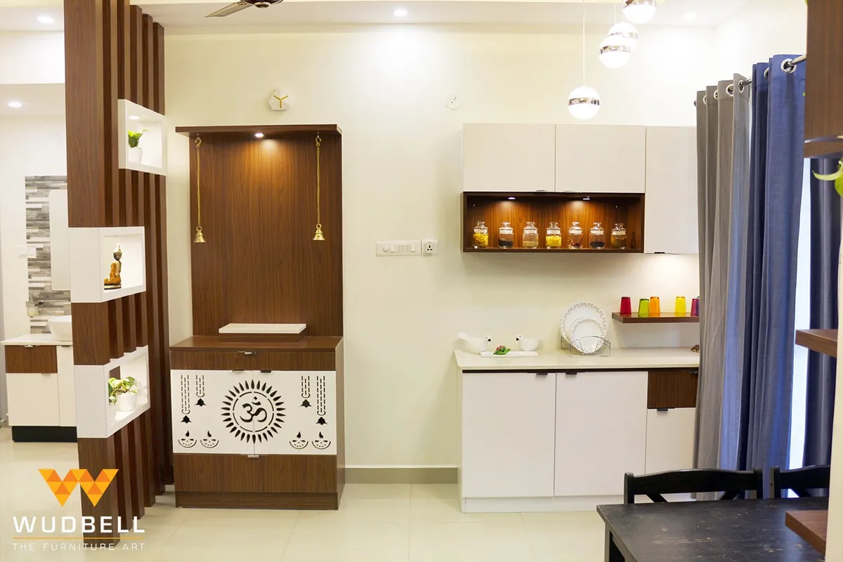 Home pooja unit in dark wood with a white jaali door cut with an Om motif and hanging brass bells