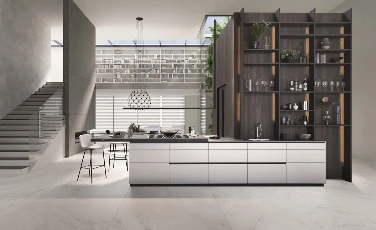 Render of a long handleless island kitchen in pale grey with a black stone top, backed by a full-height smoked-oak open shelving wall lit by vertical LED