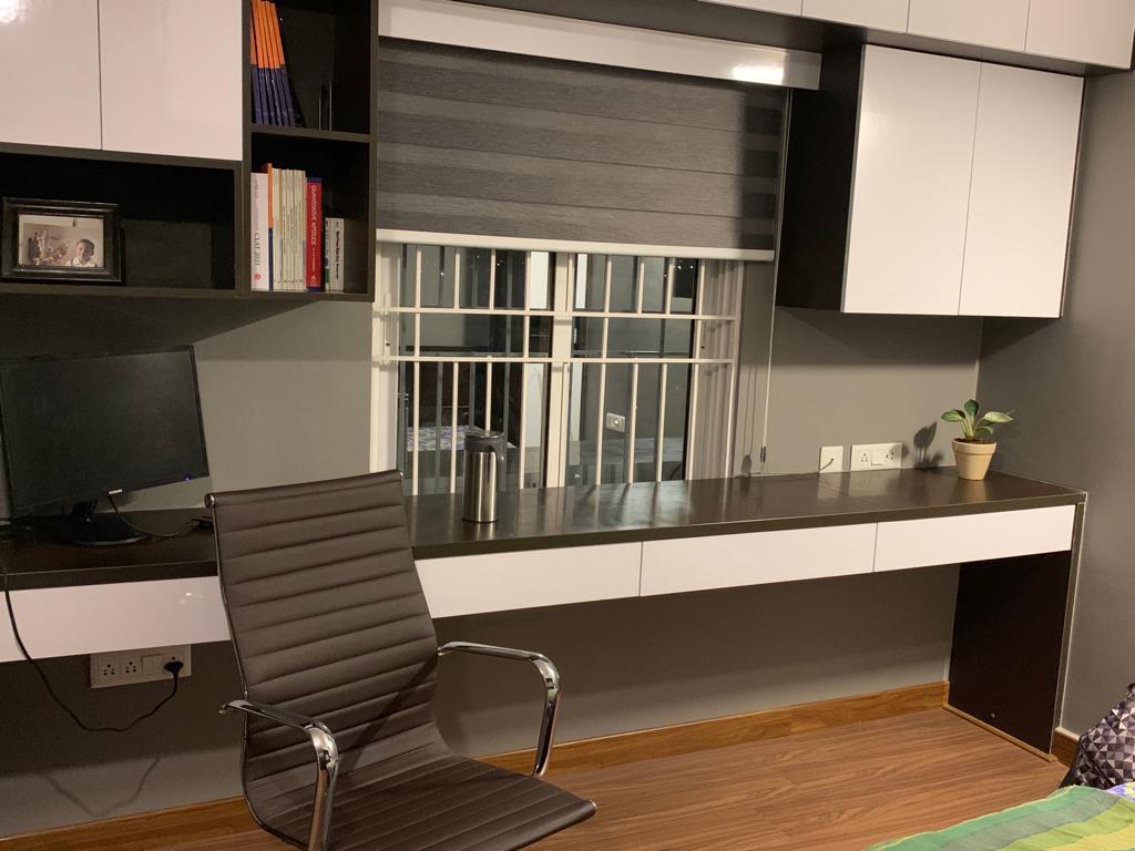 Study nook with a grey-and-white laminate desk, black leather office chair, overhead bookshelf and loft wardrobe, wood-look flooring