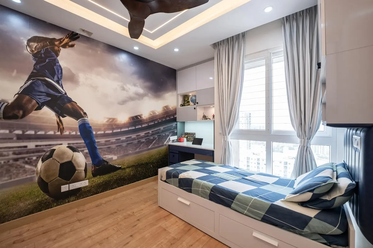 Boy's bedroom with a large football stadium mural wallpaper, a built-in study desk, and a storage bed dressed in blue check bedding