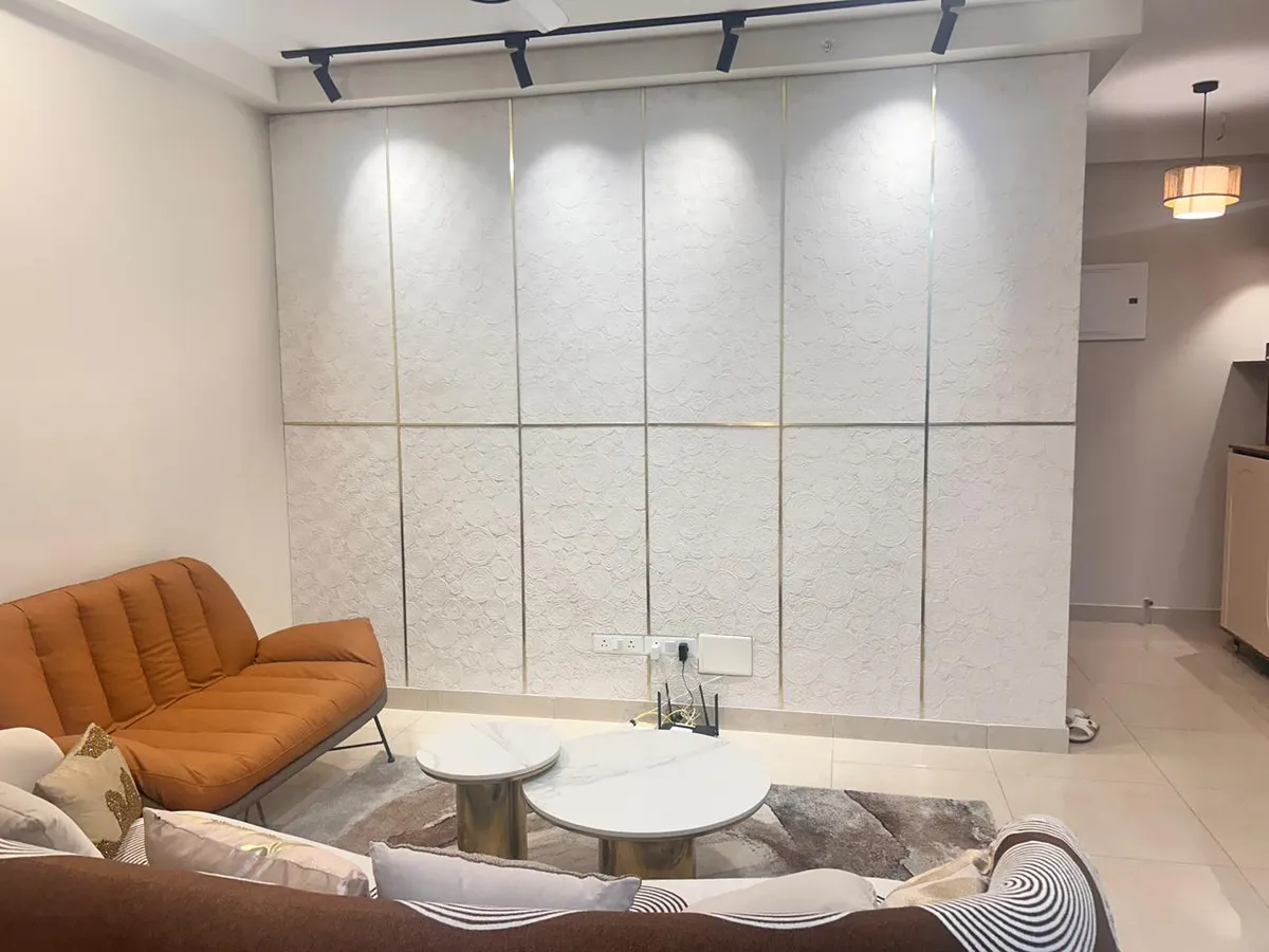 White circular-relief textured panels split by thin brass reveal strips and grazed by black track spots